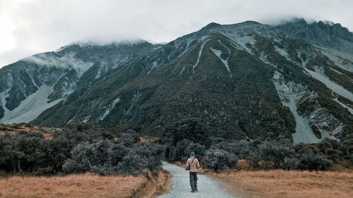 Rear view of person walking on mountain against sky