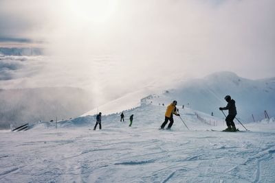 People skiing on snow covered landscape