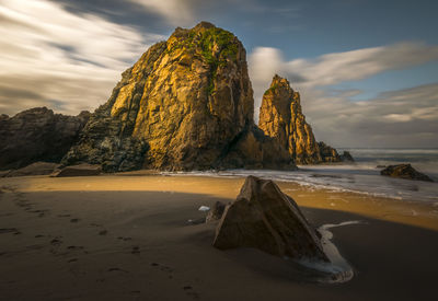 Rock formation on beach against sky