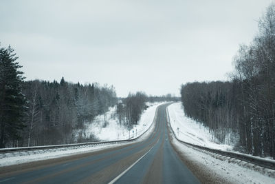 Snowfall on a winter road. an empty asphalt road without cars, covered with snow drifts. travel 