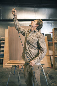 Carpenter looking up while holding cable at workshop