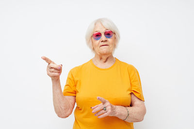 Portrait of young woman with arms raised against white background