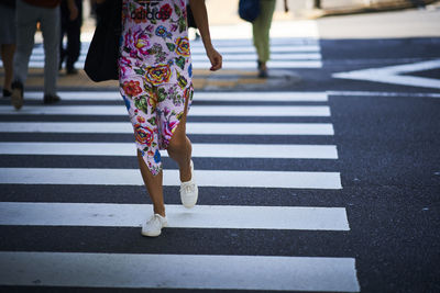 Low section of woman walking on zebra crossing