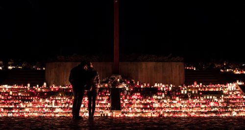 Rear view of man and woman standing at illuminated night