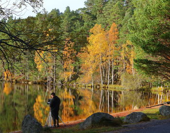 Man standing by lake in forest during autumn