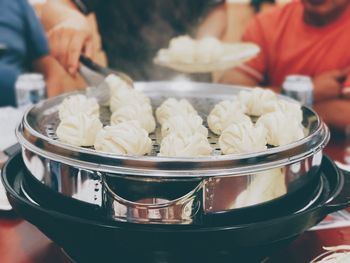 Close-up of man preparing steamed food in pot