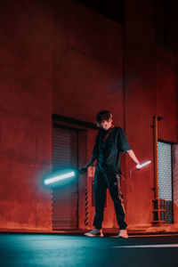 Full length of man standing against illuminated wall