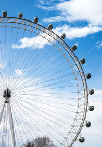 Low angle view of ferris wheel against cloudy sky