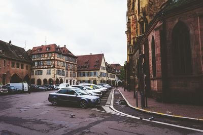 Cars on street in city against sky