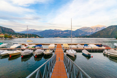 A harbour with boats and pier on lake of como, lombardy, italy at sunset