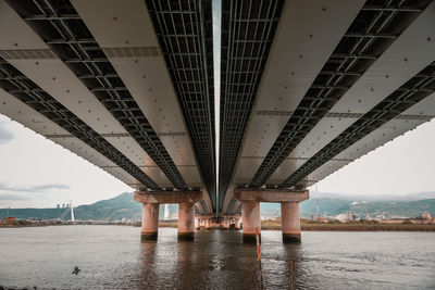 Bridge over river in city against sky