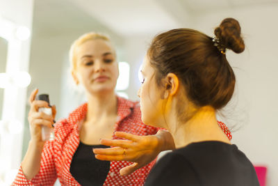 Beautician spraying hairspray to customer