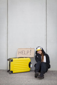 Portrait of woman sitting on yellow wall