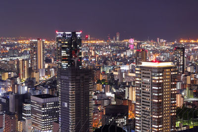 Illuminated modern buildings in city against sky at night