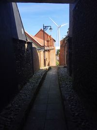 Walkway amidst buildings against sky