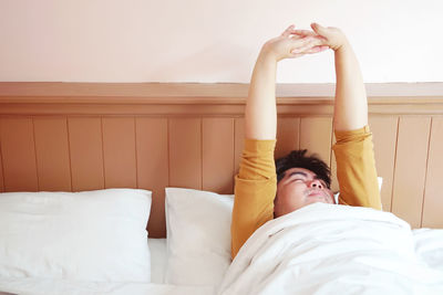 Midsection of woman resting on bed at home