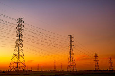 Silhouette electricity pylon on field against sky during sunset