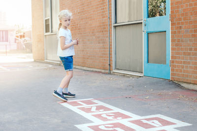 Full length of girl playing by building outdoors