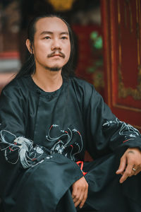 Portrait of young man looking away while standing outdoors