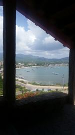 Scenic view of river and cityscape against sky seen through window