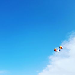 Low angle view of balloons flying against blue sky