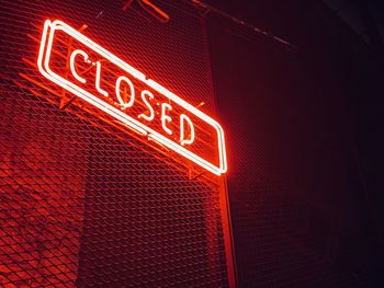 Low angle view of illuminated sign on wall at night