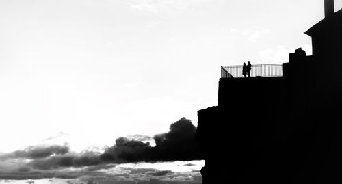 Low angle view of silhouette people standing on building against sky