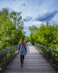 Rear view of woman on bridge against sky