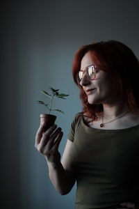 Midsection of woman holding eyeglasses while standing against plants
