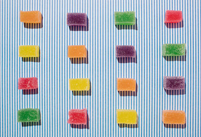 Creative colorful jelly candy pattern against blue white stripes background. flat lay