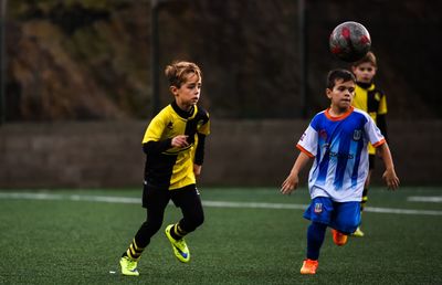 Full length of boys playing soccer on field