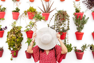 Midsection of woman holding red flowers in potted plant