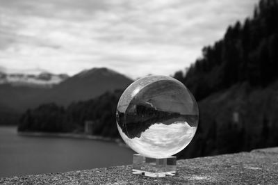 Close-up of crystal ball with reflection on mountain against sky