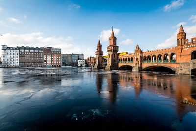Oberbaum bridge over frozen spree river against sky