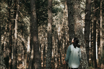 Rear view of woman standing in forest