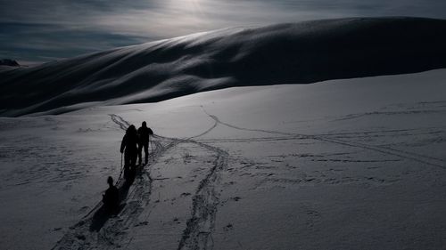 Silhouette hikers on snowcapped mountain