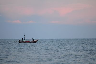 Man sailing on sea against sky during sunset