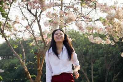 Portrait of young woman standing against trees