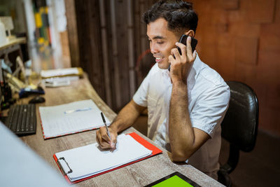 Side view of young man using mobile phone