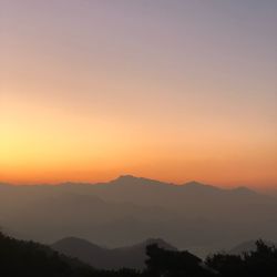 Scenic view of silhouette mountains against orange sky