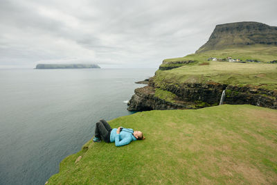 Man sitting in sea against sky