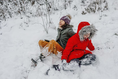 Cheerful sisters playing in snow during winter