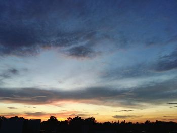 Silhouette of trees against dramatic sky