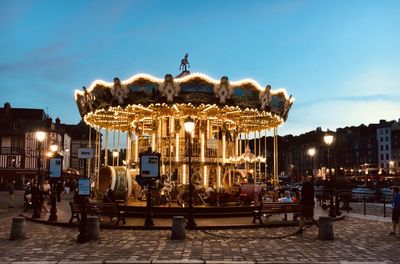 Illuminated amusement park against sky at dusk