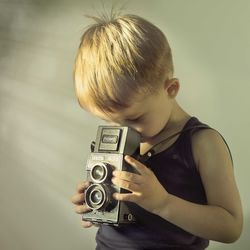 Boy photographing by analog camera at home