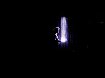 Silhouette man standing by illuminated lights at night