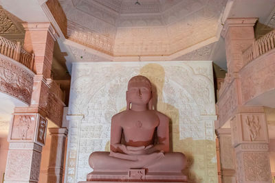 Isolated red stone jain god holy statue in meditation from different angle