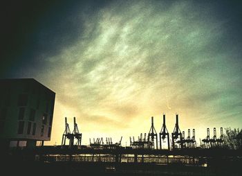 Low angle view of crane against cloudy sky