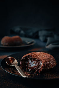 Close up of molten chocolate lava cake on black plate with dark background