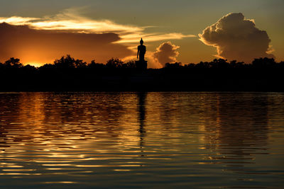 Silhouette trees by lake against sky during sunset